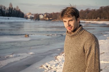 Adam üzerinde fotokopi alanı olan bir kazak giyiyor. Kışın açık havada kazak giyen adam. Açık havada kışın süveter giyen şık bir adam. Tatillerde kazak giyen adam..
