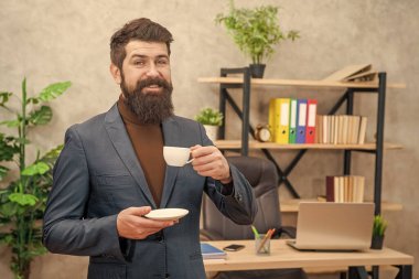 cheerful bearded businessman drinking coffee in the office with copy space, business.