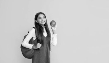 positive child with school backpack and apple on yellow background.