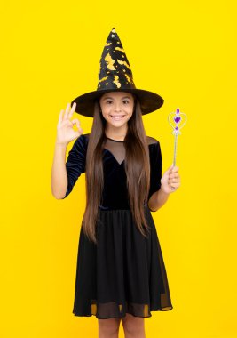 Şeker mi şaka mı? Cadılar Bayramı partisi. Tüm Cadılar Bayramı cadıları. 31 Ekim. Cadı kostümlü genç kız sihirli değneği tutuyor. Mutlu Cadılar Bayramı. Cadılar Bayramı kostümlü cadı kız sarıda izole edilmiş. Tamam..