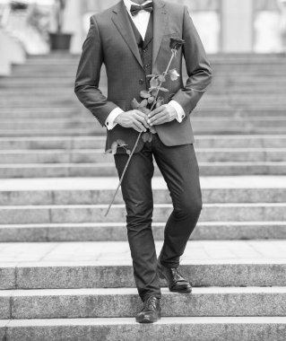 cropped view of elegant man in tuxedo at romantic occasion. man with romantic present. handsome romantic man with rose.