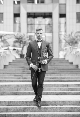 Smokinli şık bir adam. Smokin giymiş, papyonlu bir adam. Kırmızı güllü beyaz smokinli adam..