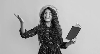 positive child with frizz hair recite book on yellow background.