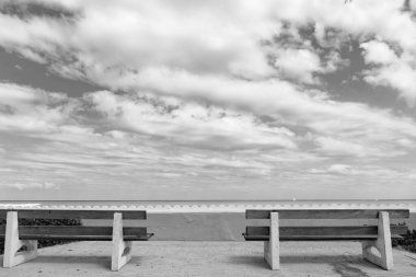 Bulutlu gökyüzü ve deniz manzaralı boş ahşap bank.