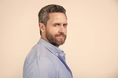 Stüdyoda sakallı, olgun bir adamın portresi. Sakallı, olgun bir adamın fotoğrafı. Kirli sakallı, normal gömlekli olgun bir adam. Gri arka planda sakallı, olgun bir adam..