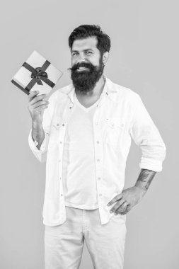 Sarıya izole edilmiş hediye kutusu olan neşeli bir adam. Stüdyoda hediye kutusu olan bir adam. Arka planda hediye kutusu olan bir adam. Hediye kutusu olan adamın fotoğrafı..