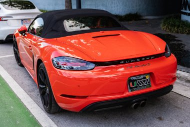 Miami Beach, Florida USA - 9 Haziran 2024: 2018 Porsche 718 Boxter 's orange color at Miami Beach. Ocean 'daki lüks Porsche Miami plajına gidiyor. arka plan