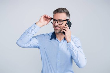 Gözlüklü bir adam telefonda konuşuyor. Telefonu olan olgun bir iş adamı. İş iletişimi. İş adamının Grey 'den izole edilmiş bir telefon görüşmesi var. Telefon kullanan bir iş adamı. Telefon görüşmesi..
