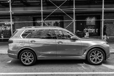 New York City, USA - August 05, 2023: 2023 BMW X7 xDrive40i SUV gray car passenger side view, parked next to scaffolds. clipart