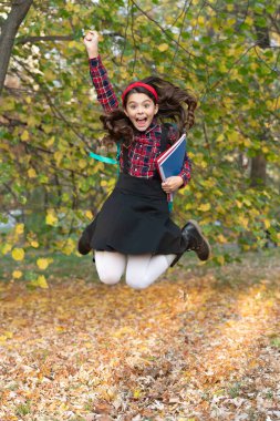 Okula dönelim. Ödevleri olan genç kız sonbaharda atlıyor. Kızların okul eğitimi. Bilgi ve eğitim. Sonbahar indirimi. Bilgi toplama günü. Sonbahar okulu ödevinde atlayan kız. Çocukluk mutluluğu.