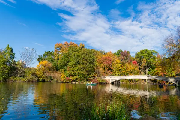 New York City, ABD - 25 Ekim 2023: Gölde teknesi olan Central Park. Sonbahar resmedilmeye değer manzara. Central Park 'ta kürek çeken insanlar. Sonbahar ağaçlı Central Park. Sonbahar doğası.