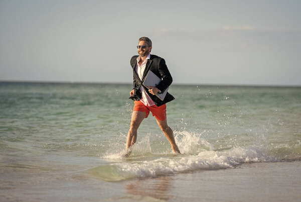 успех бизнеса бизнесмена. Бизнесмен в костюме с ноутбуком в море. успешный бизнесмен в гидрокостюме на пляже. бизнесмен работает на летних каникулах. деловой путешественник.