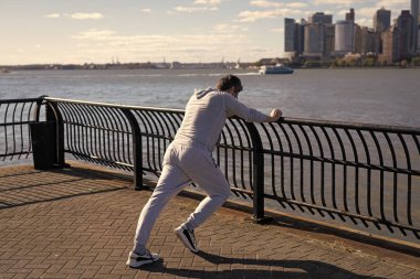 Sporcu koştuktan sonra kaslarını esnetiyor. Sporcu esnekliği artırmak için esneme hareketi yapar. Spor adamı antrenman için ısınıyor. New York 'ta sporcunun esneme hareketleri. Buzağı esnemesi.