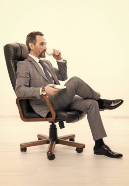 Ofis müdürü beyazları izole etmiş. Takım elbiseli iş adamı. Büyük patron. İş adamı kahve içiyor. Ofis koltuğundaki iş adamı. İş liderliği ve başarı. Görevde başarılı bir iş adamı.