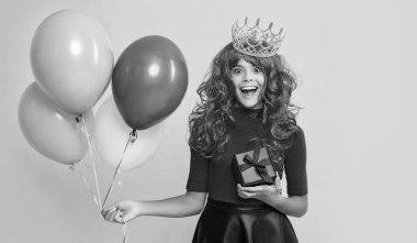 happy child in crown with gift box and party balloon on yellow background. wow.