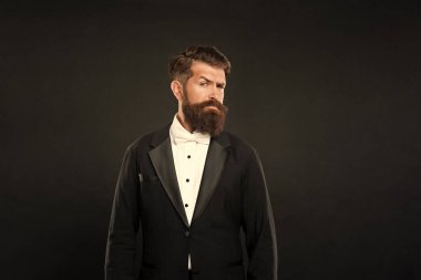 Smokinli papyonlu ciddi sakallı adam. Siyah arka planda resmi giyimli uşak. erkek resmi moda.