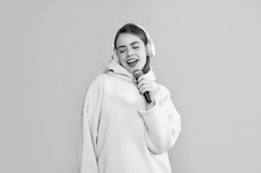 Sarı arka planda mikrofonu olan kulaklıklı genç kız..