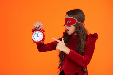 Parti geri sayımı. Parti maskeli, saati olan genç bir kız. Parti sonrası eve geç gelen bir kız. Tatil eğlencesi bitti. Geri sayım. Geç kalan kız turuncudan izole edilmiş. Geç saatte. İşaret parmağı.