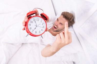 Erken kalkmak. Uyanma ve kalkma vakti geldi. Sabah uyanması. Yatakta yatarken çalar saati olan kızgın bir adam. Sabah uyanışı. Uykulu adam çalar saati kapatıyor. Orta parmak gösteriliyor.