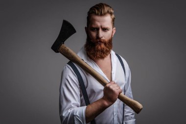 Yakışıklı ve karizmatik. Erkeksi adam. Baltası gri renkte olan sakallı bir adamın erkekliği. Sakallı ve bıyıklı, beyaz, vahşi bir adam. Erkeksi enerji. Retro tarzı. Klasik kuaförlük.