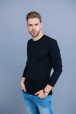 Tıraşsız yüzlü, kendine güvenen genç bir adam ve gri üzerinde izole bir saç stili..
