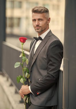 Nişan tarihi. Smokinli adam nişanı kutluyor. Nişan için gül hediyeli gülümseyen adam..