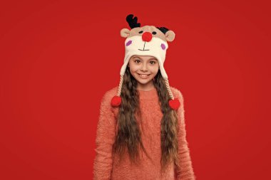 Kış çocuk kıyafetleri. Xmas şapkalı genç kız kırmızıda izole edilmiş. Gençler için kış modası. Kış mevsiminde örgü şapkalı bir kız. Çocukluk yaşam tarzı.