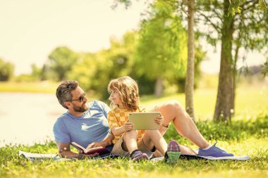Baba ve oğul parkta rahatlayın. çocukluk okulu eğitimi. Oğlu ve babası yazın kaynaşıyorlar. Baba ve oğul eğitimi. Baba oğul eğitimini kitap ve tabletle şekillendirir. Doğa harikaları..