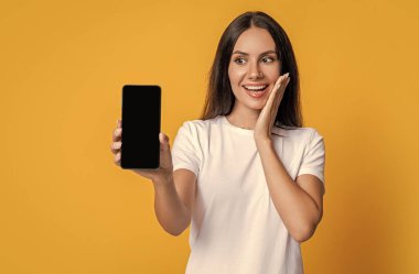 Ürün teklifi. Reklam sunumu kopyalama alanı. Telefon ekranı sunan bir kadın. Sarıda izole akıllı telefon gösteren bir kadın. Telefon uygulaması gösteren bir kadın. Sunulan günlük.