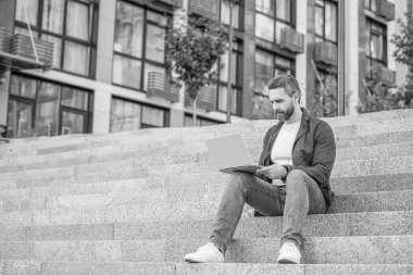 Bilgisayarlı serbest çalışan bir adamın reklam fotoğrafı. Dışarıda dizüstü bilgisayarı olan serbest çalışan bir adam. Sokaktaki serbest çalışan adam. Dışarıda polisle serbest çalışan bir adam..