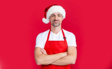 Kırmızı kahve önlüklü ve Noel Baba şapkalı olgun bir adam..