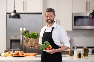 Sağlıklı beslenme, vejetaryen. Akşam yemeği için sağlıklı yemek. İspanyol adam mutfakta yemek hazırlıyor. Aşçı adam evde sağlıklı yemek pişiriyor. Mutfaktaki adam. Salata at..