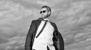 Takım elbiseli olgun patronun fotoğrafı. Gökyüzü geçmişinde takım elbiseli patron. Takım elbiseli patron dışarıda. Takım elbiseli patron..