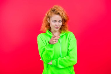 Sıradan bir yaşam tarzı. Havalı kapüşonlu giyen kızıl saçlı kız. Pembe üzerine izole edilmiş şık bir kadın. Hareketli moda kız kapüşonlu giyer. Moda kıyafetleri ve tarzı. Kazaklı beyaz bir kadın. İşaret parmağı.