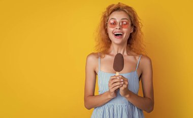 Arka planda dondurmalı ve fotokopi alanı olan bir kadın. Yazın dondurmalı bir kadının fotoğrafı. Dondurmalı kadın sarıda izole edilmiş. Stüdyoda dondurmalı kadın..