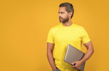 man blogger isolated on yellow, copy space. man blogger on background. man blogger in studio. photo of man blogger with laptop. clipart