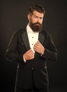 bearded man in tuxedo on black background, bow tie.