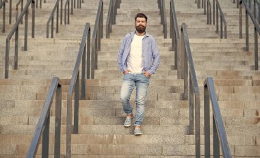 Sakallı adam aşağı iniyor. Uzun boylu, sakallı bir adam. Merdivenlerdeki hippi çocuk..