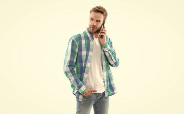 Genç adamın beyaz arka planda izole edilmiş bir telefon görüşmesi var. Stüdyoda sıradan bir adam telefona cevap veriyor. Telefondaki adam kareli gömlek giyiyor. Fotoğrafta telefon görüşmeleri var..