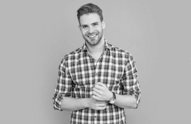 Sıradan tarzda neşeli bir adam. Stüdyo fotoğrafı. Sakallı beyaz bir adam. Gri arka planda kareli gömlekli yakışıklı bir adam izole edilmiş..