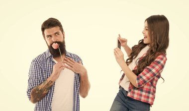 Kamera ayarları. Fotoğraf düzenleme başvurusu. Küçük mutlu kızın elinde akıllı telefon ya da cep telefonu beyaz arka planı var. Mobil fotoğrafçılık. Babasının fotoğrafını çeken bir kız. Geleceğin fotoğrafçısı..