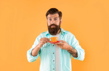 upset hipster with beard holding coffee cup on yellow background, barista.