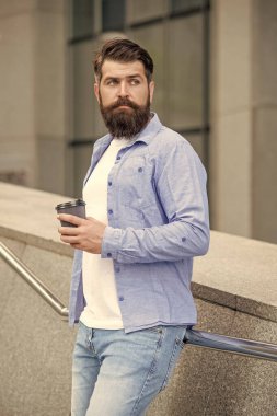 Sakallı adam dışarıda kahve içiyor. Adam sokakta kahve içiyor. Kahve içen bir adamın fotoğrafı. Adam dışarıda kahve içiyor..