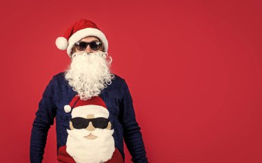 Noel Baba kostümlü mutlu sakallı adam kış bayramını kutluyor ve Noel hediyeleri, parti eğlencesi, fotokopi uzayı hakkında seviniyor..