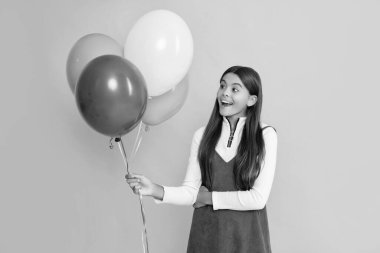 happy girl with party colorful balloons on yellow background.