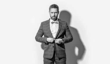 Karizmatik adam smokin giyer. Gri arka planda smokinli adam. Stüdyodaki smokinli adam. Smokin giyen adamın fotoğrafı..