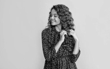child smile with long brunette curly hair on yellow background.