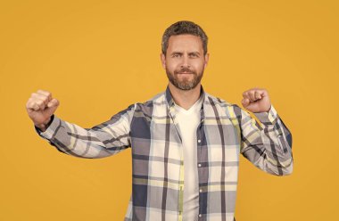 Gömlekli beyaz sakallı adam sarıda yalnız eğleniyor. Kafkasyalı sıradan bir adam stüdyoda eğleniyor. Beyaz adamın kareli gömlek giydiği eğlenceli bir fotoğraf. Kafkasyalı bir adamın sıradan giyinmesi eğlencelidir..