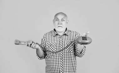 amazed aged man with retro telephone on yellow background.