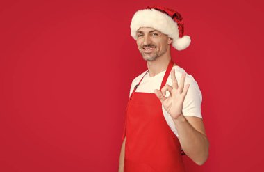 Kırmızı önlüklü ve Noel Baba şapkalı mutlu bir kafeterya sahibi. Tamam.